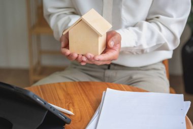 Muhasebeci, iş adamı, emlakçı, iş adamı müşterilere model ev veriyor. Müşterilerin imzalaması için ev faizi hesapları dökümanları da var..