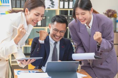 Takım işi üç gülümseyen ve mutlu Asyalı erkek ve kadın takımı tablet ve dizüstü bilgisayarları kullanarak şirket içindeki bir şirket çizelgesinde istatistikler oluşturuyorlar. Meslektaşlar konsepti.