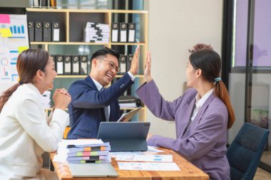 Takım işi üç gülümseyen ve mutlu Asyalı erkek ve kadın takımı tablet ve dizüstü bilgisayarları kullanarak şirket içindeki bir şirket çizelgesinde istatistikler oluşturuyorlar. Meslektaşlar konsepti.
