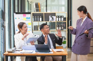 Asyalı iş adamları pazarlama personelinden oluşur. Muhasebeci ve finans görevlisi tabletleri kullanarak şirket kârlarını analiz etmede birbirlerine yardımcı oluyorlar. Hesap makinesi, dizüstü bilgisayar, grafik kağıdı ve şirket kalemleri..