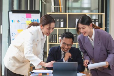 Bir grup işadamı, kazançları için dizüstü bilgisayarları ve grafik çizelgeleriyle plan yapar ve şirketlerinin yıllık bakiyesini hesaplamak için bir hesap makinesi kullanır..