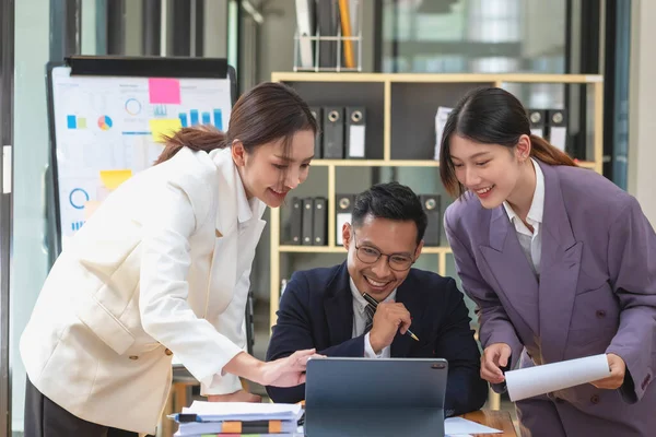 Bir grup işadamı, kazançları için dizüstü bilgisayarları ve grafik çizelgeleriyle plan yapar ve şirketlerinin yıllık bakiyesini hesaplamak için bir hesap makinesi kullanır..