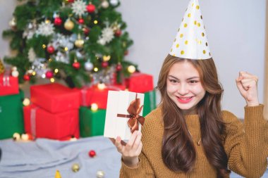 Mutlu Noeller ve mutlu tatiller! Sarı gömlekli güzel yüzlü genç bir kadın Noel ağacı süslenmiş bir evde hediye kutularıyla neşe gösteriyor. Xmas 'tan Önce Portre