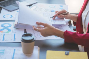 Finansal, kırmızı takım elbiseli Asyalı iş kadını elinde bir fincan kahveyle ofiste oturuyor, iş yerindeki muhasebe işlerini yapmak için bilgisayara sahip olmak, yıllık iş karını hesaplamak, iş fikrini...