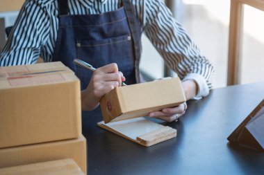 Asyalı bir iş kadını, internet üzerinden ürün satarak, çevrimiçi bir mağaza açarak ve ofis içinde müşteri paketlerinden sipariş alarak KOBİ işini seviyor. KOBİ İş Konsepti.