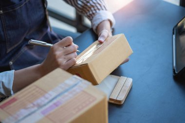 Asyalı bir iş kadını, internet üzerinden ürün satarak, çevrimiçi bir mağaza açarak ve ofis içinde müşteri paketlerinden sipariş alarak KOBİ işini seviyor. KOBİ İş Konsepti.