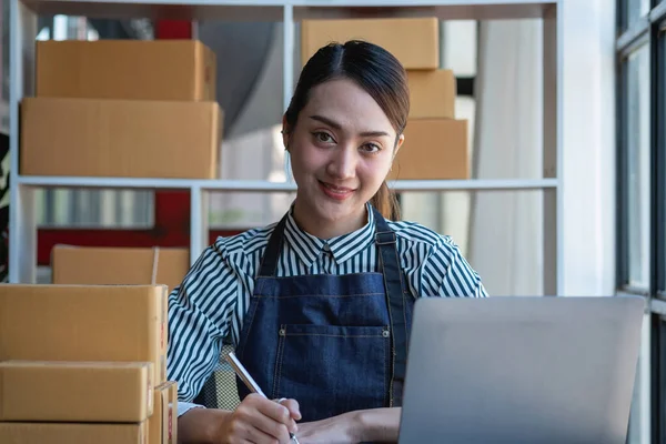 stock image An Asian businesswoman enjoys his online SME business selling products, profiting from opening an online store, and taking orders for customer parcels inside the office. Concept SME Business.