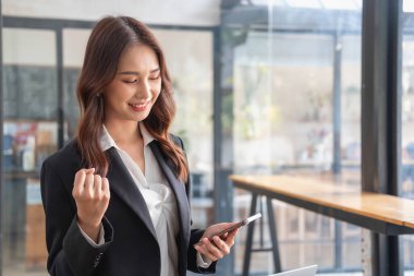 Pazarlama, Finansal, Muhasebe, Planlama, Asyalı kadın girişimci elinde akıllı bir telefonla şirketin işletme yönetiminden kazanç elde etmeyi başardığını ifade ediyor..