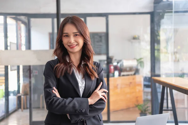Marketing, Financial, Accounting, Planning, Smiling businesswoman standing with arms crossed happily leading a profitable business management team inside the office.