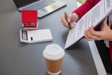 Muhasebeci, iş adamı, emlakçı, iş adamı müşterilere model ev veriyor. Müşterilerin imzalaması için ev faizi hesapları dökümanları da var..