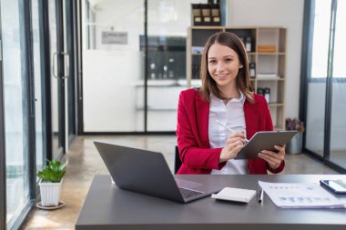 Pazarlama, Finansal, Muhasebe, Planlama, Şirket Başkanı elinde tablet, hesap makinesi, kalem ve grafik kağıdıyla ofisinde oturuyor..