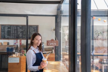 Portrait of a woman, a coffee shop business owner smiling beautifully and opening a coffee shop that is her own business, Small business concept.	