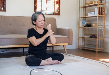 Asyalı yaşlı bir kadın iyi sağlık için yoga yaparken yaşlı bir kadın, rahatlatıcı bir günde evde vücudunun sağlığıyla ilgilenir. iyi sağlık kavramı