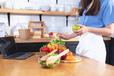 Diyet, beyaz tenli, mavi gömlekli genç Asyalı kadın sağlıklı bir diyet olarak sebze salatası ve elma yiyor, abur cubur yemeyi tercih ediyor. Kadın beslenme uzmanı kilo veriyor. sağlıklı yeme kavramı.