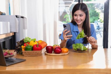 Diyet, beyaz tenli, mavi gömlekli genç Asyalı kadın sağlıklı bir diyet olarak sebze salatası ve elma yiyor, abur cubur yemeyi tercih ediyor. Kadın beslenme uzmanı kilo veriyor. sağlıklı yeme kavramı.