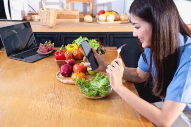 Diyet, beyaz tenli, mavi gömlekli genç Asyalı kadın sağlıklı bir diyet olarak sebze salatası ve elma yiyor, abur cubur yemeyi tercih ediyor. Kadın beslenme uzmanı kilo veriyor. sağlıklı yeme kavramı.