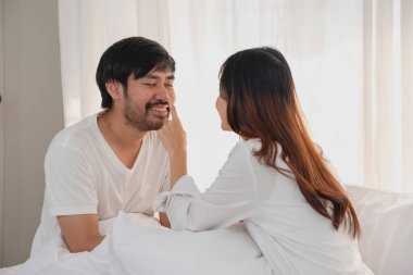 Mutlu Asyalı genç çift kucaklaşıyorlar, takılıyorlar, evde neşeyle yatakta oynuyorlar, aile bağlarını geliştirmek için romantik zaman. aile kavramı.