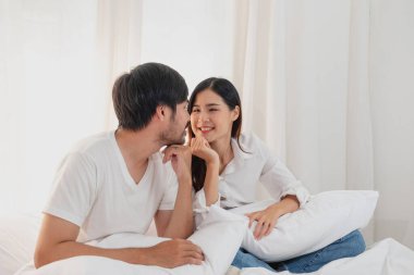 Mutlu Asyalı genç çift kucaklaşıyorlar, takılıyorlar, evde neşeyle yatakta oynuyorlar, aile bağlarını geliştirmek için romantik zaman. aile kavramı.