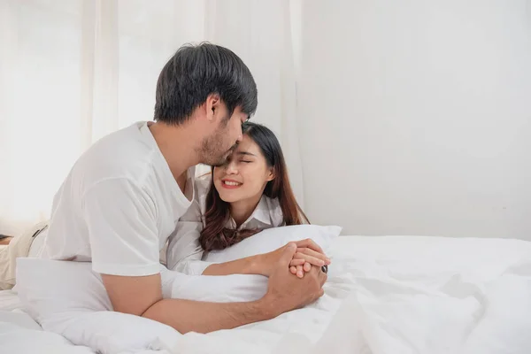 stock image Happy young asian couple embracing, teasing, playing cheerfully in bed at home, romantic time to enhance family bonding. family concept.