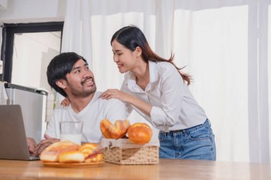 Meyve sebzelerle yemek yapan ve mutfakta dizüstü bilgisayar kullanan genç Asyalı çift aile içinde birlikte yemek pişiriyor. Aile kavramı..