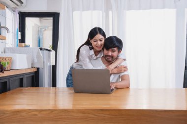 Meyve sebzelerle yemek yapan ve mutfakta dizüstü bilgisayar kullanan genç Asyalı çift aile içinde birlikte yemek pişiriyor. Aile kavramı..