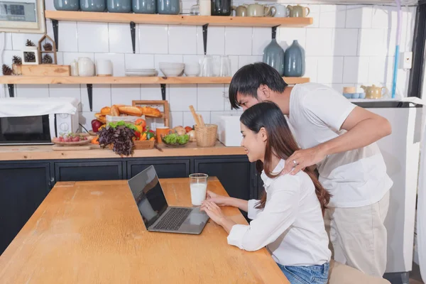 stock image Young Asian couple cooking with fruits and vegetables and using laptop in the kitchen To cook food together within the family happily, family concept.