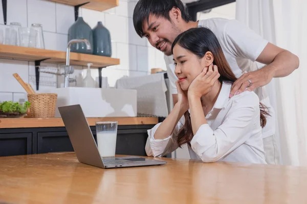 Meyve sebzelerle yemek yapan ve mutfakta dizüstü bilgisayar kullanan genç Asyalı çift aile içinde birlikte yemek pişiriyor. Aile kavramı..