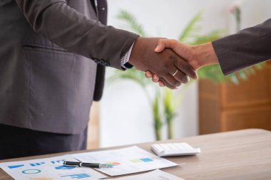 Tatmin olmuş siyah müvekkil, başarılı iş görüşmelerinden sonra Afrikalı Amerikalı iş adamlarının el sıkışması için müdüre teşekkür ediyor. Kiralıyorum. Satın alma hizmetleri.