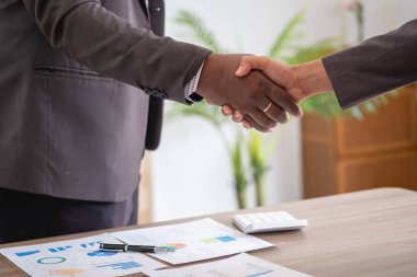 Tatmin olmuş siyah müvekkil, başarılı iş görüşmelerinden sonra Afrikalı Amerikalı iş adamlarının el sıkışması için müdüre teşekkür ediyor. Kiralıyorum. Satın alma hizmetleri.