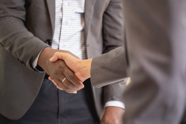Tatmin olmuş siyah müvekkil, başarılı iş görüşmelerinden sonra Afrikalı Amerikalı iş adamlarının el sıkışması için müdüre teşekkür ediyor. Kiralıyorum. Satın alma hizmetleri.