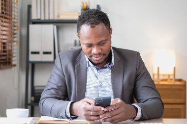 Akıllı telefon ve dizüstü bilgisayardan şirket sonuçlarını okurken Afro-Amerikalı siyahi adam mutlu oluyor. İş finans ve teknoloji kavramları.