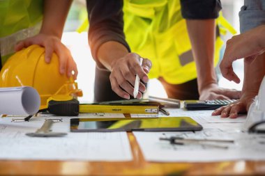 Asyalı mühendisler maliyet tahminlerini belgelemek ve evler ve binalar için mimari ve mühendislik tasarımları için kat planları yazmak için beyin fırtınası yapıp ölçüm yapıyorlar..