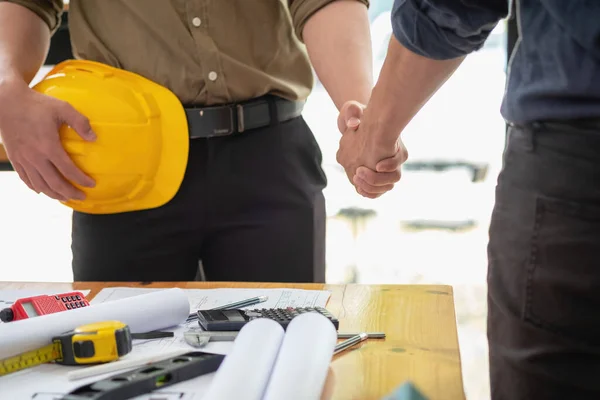 Asian engineers stand hand in hand to work together to document cost estimates and write floor plans for architectural and engineering designs for houses and buildings.