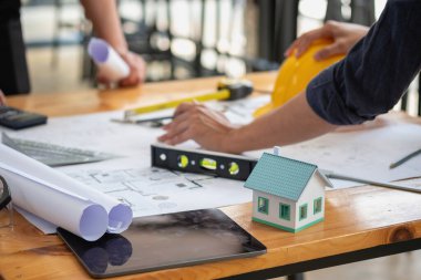 Asyalı mühendisler maliyet tahminlerini belgelemek ve evler ve binalar için mimari ve mühendislik tasarımları için kat planları yazmak için beyin fırtınası yapıp ölçüm yapıyorlar..