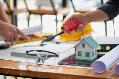 Asyalı mühendisler maliyet tahminlerini belgelemek ve evler ve binalar için mimari ve mühendislik tasarımları için kat planları yazmak için beyin fırtınası yapıp ölçüm yapıyorlar..