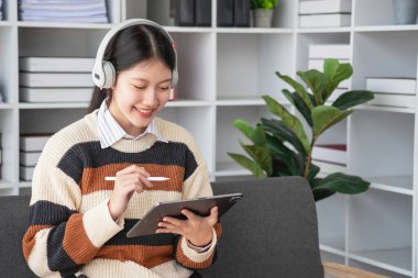 Asyalı kız öğrenciler çevrimiçi çalışıyor, evde kalıyor, öğretmenlik yapıyor, video çekiyor ve internette yakınlaştırıyor. İnternette bilgisayar, tablet ve cep telefonuyla İngilizce öğrenen mutlu Asyalı kız. çevrimiçi öğrenme kavramı.