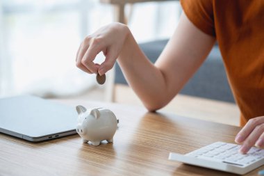 Genç Asyalı kadın emeklilik için para biriktiriyordu. Kumbaradan para biriktiriyordu ve defter, tasarruf konsepti gibi notlar alıyordu..