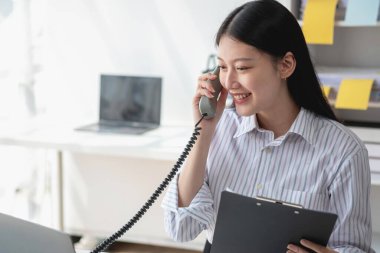 Asyalı iş kadını telefonda konuşuyor. Modern ofiste müşterilerle konuşuyor. Ofiste yeni bir iş yapma şekli için..
