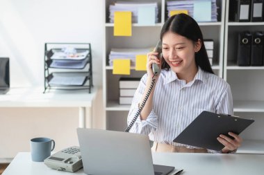 Asyalı iş kadını telefonda konuşuyor. Modern ofiste müşterilerle konuşuyor. Ofiste yeni bir iş yapma şekli için..
