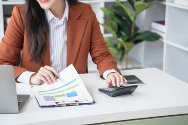 Ofiste çalışan iş kadını mali raporları hesaplamak için hesap makinesi kullanıyor. Bilgisayarlı satış verileri ve ofis masasında iş belgeleri. Kapatın. İş finans ve yatırım.