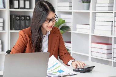 Ofiste çalışan iş kadını mali raporları hesaplamak için hesap makinesi kullanıyor. Bilgisayarlı satış verileri ve ofis masasında iş belgeleri. Kapatın. İş finans ve yatırım.