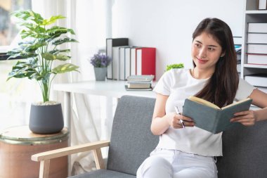 rahat bir koltukta oturan ve planlayan bir kadın hesap makinesi ve ev, masa, sigorta ve konut, kredi ve ikamet bütçesi, iş ve mülkiyet konseptiyle gider ve ipotek hesapları yapar..