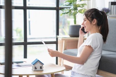 rahat bir koltukta oturan ve planlayan bir kadın hesap makinesi ve ev, masa, sigorta ve konut, kredi ve ikamet bütçesi, iş ve mülkiyet konseptiyle gider ve ipotek hesapları yapar..