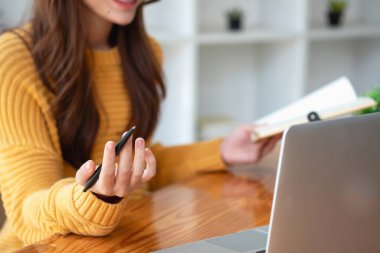 Mutlu Latin kız kolej öğrencisi uzaktan öğrenim kursu, uzak üniversite web sitesi ya da laptop üzerinden konuşma videosu alıyor ve evdeki ya da kampüsteki sanal toplantı seminerinde not defteri kullanıyor.