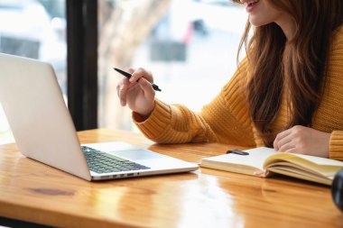 Mutlu Latin kız kolej öğrencisi uzaktan öğrenim kursu, uzak üniversite web sitesi ya da laptop üzerinden konuşma videosu alıyor ve evdeki ya da kampüsteki sanal toplantı seminerinde not defteri kullanıyor.