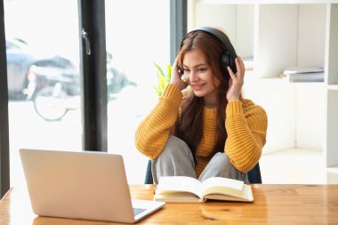 Mutlu Latin kız kolej öğrencisi uzaktan öğrenim kursu, uzak üniversite web sitesi ya da laptop üzerinden konuşma videosu alıyor ve evdeki ya da kampüsteki sanal toplantı seminerinde not defteri kullanıyor.