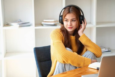 Mutlu Latin kız kolej öğrencisi uzaktan öğrenim kursu, uzak üniversite web sitesi ya da laptop üzerinden konuşma videosu alıyor ve evdeki ya da kampüsteki sanal toplantı seminerinde not defteri kullanıyor.
