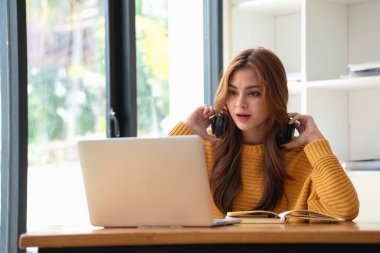 Mutlu Latin kız kolej öğrencisi uzaktan öğrenim kursu, uzak üniversite web sitesi ya da laptop üzerinden konuşma videosu alıyor ve evdeki ya da kampüsteki sanal toplantı seminerinde not defteri kullanıyor.