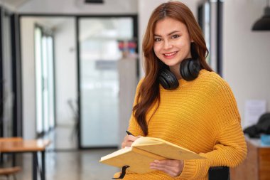 Mutlu Latin kız kolej öğrencisi uzaktan öğrenim kursu, uzak üniversite web sitesi ya da laptop üzerinden konuşma videosu alıyor ve evdeki ya da kampüsteki sanal toplantı seminerinde not defteri kullanıyor.