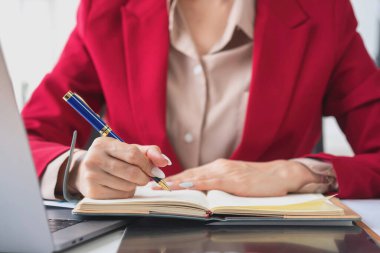 Genç Asyalı güzel iş kadını not defterini kullanarak mali belge, vergi, döviz, muhasebe ve mali danışman üzerinde çalışmayı planlıyor..